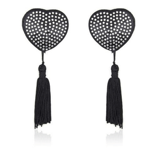 Coppia di copricapezzoli neri a forma di cuore con strass chiari e lunghe nappine nere, fotografati su sfondo bianco.