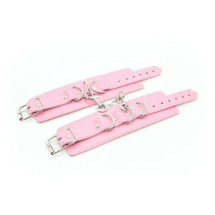 Polsini rosa in ecopelle aperti e distesi con anelli metallici e moschettone centrale, vista dall’alto su sfondo bianco.