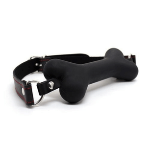 Morso in silicone nero a forma di osso con cinturino regolabile e dettagli metallici, vista angolata laterale.