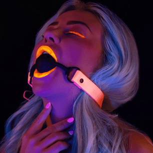Primo piano ball gag glow in the dark Taboom con palla luminosa arancione fluorescente e cinturino rosa regolabile
